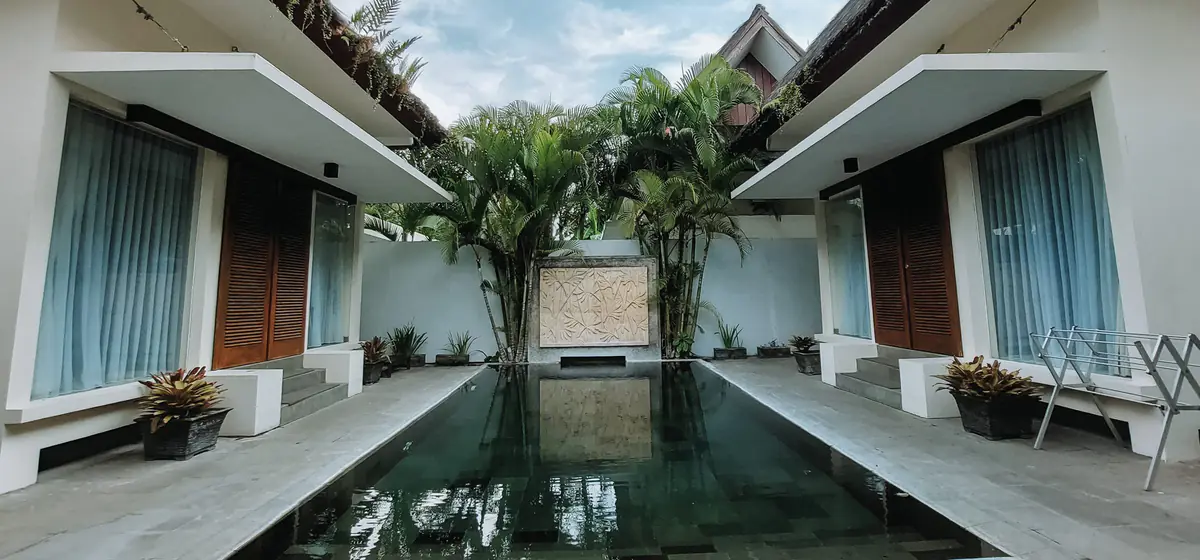 Halaman berumput di tepi kolam dengan bungalow di kejauhan